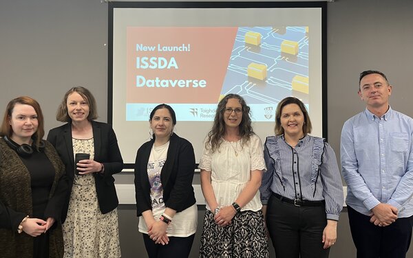 A picture of the ISSDA Dataverse implementation team standing in front of a screen showing a picture from the launch. 